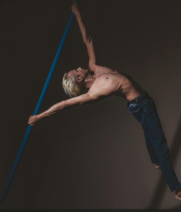 Man performing a controlled strength exercise in a dark, minimalist setting with lime green light accents.